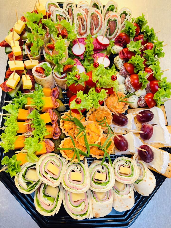 Schotel met hapjes van Catering bij Natalia: wraps, spiesjes met kaas en worst, tartaletjes en druiven.