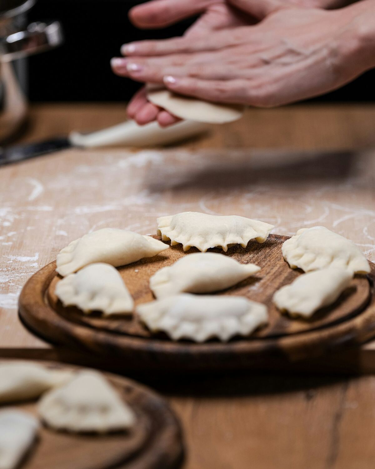 Handen die pierogi dichtknijpen op een met bloem bestoven werkblad.