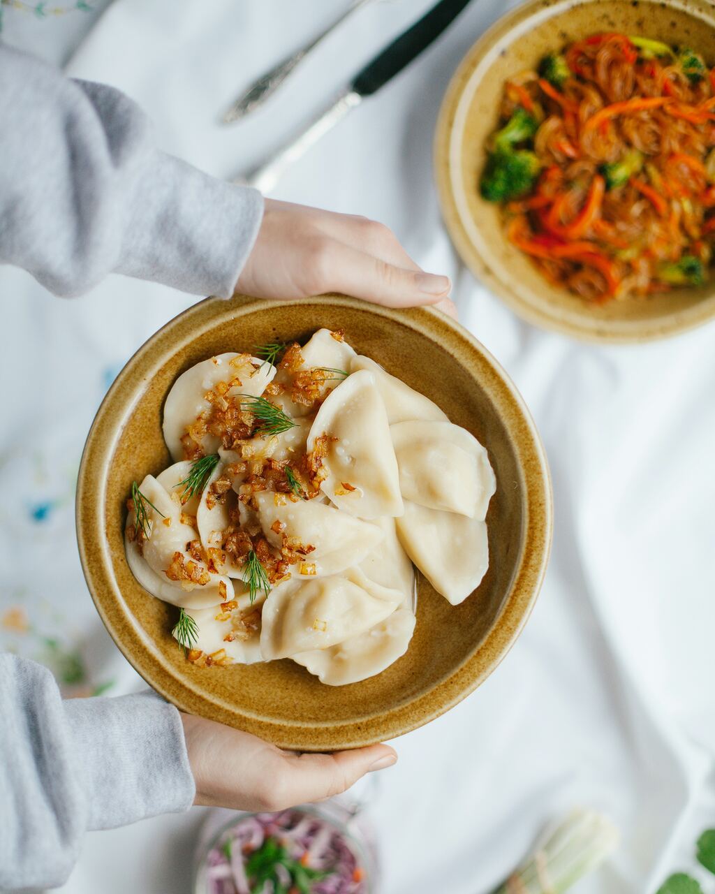 Pierogi met gebakken ui en dille in een aardewerken kom.